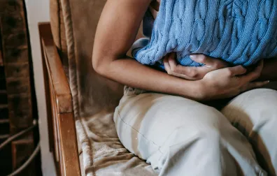 Vrouw op stoel houdt haar buik vast