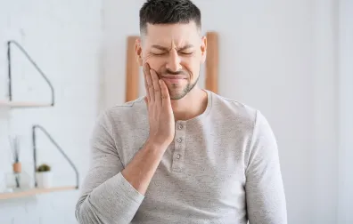 Man legt hand op wang tegen pijnlijke kies