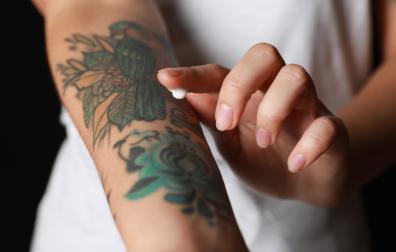 Vinger smeert creme op tattoo