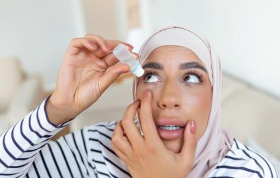 Vrouw met hoofddoek brengt oogdruppels aan in oog