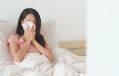 Vrouw ligt in bed en snuit neus