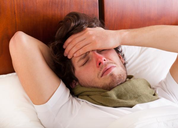 man ligt met griep in bed