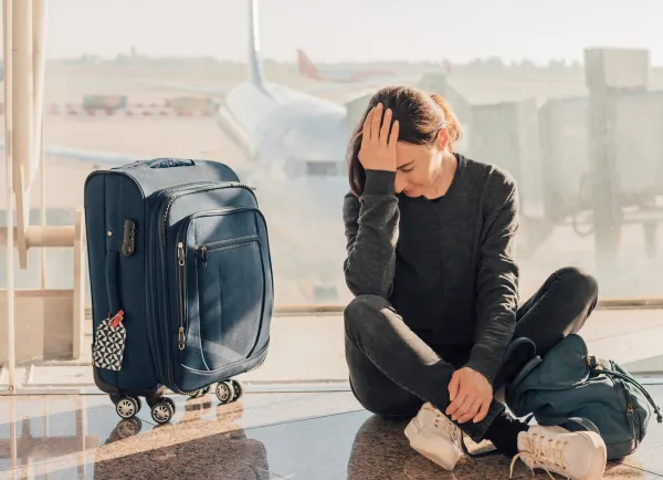 Vrouw zit naast koffer op vliegveld met jetlag
