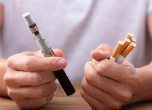 Twee handen houden vape en sigaretten vast